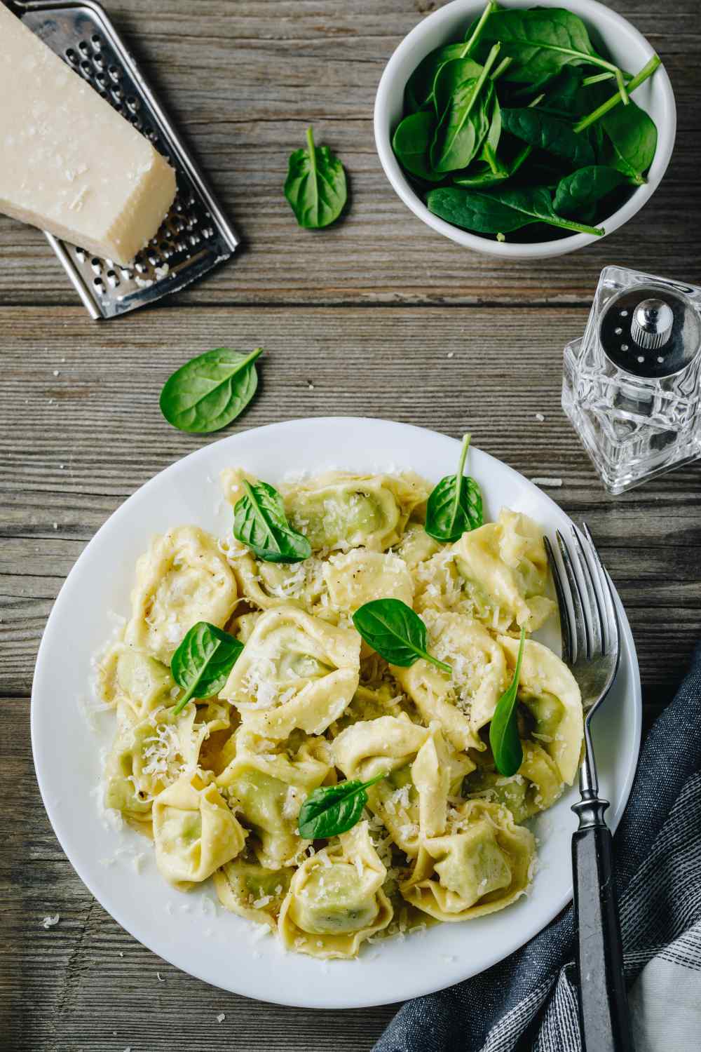 Tortellini auf Teller mit Käse und Basilikum garniert